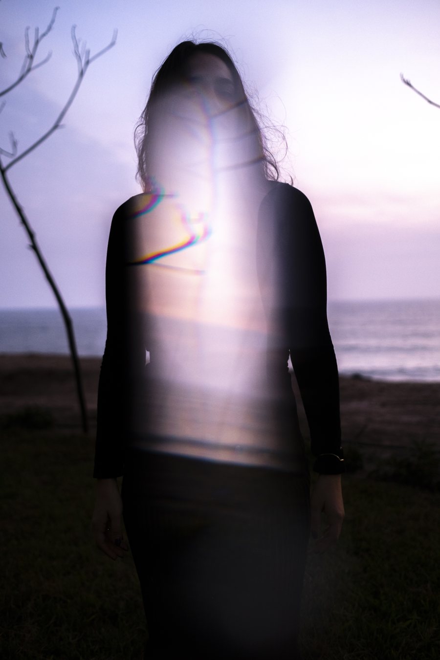 Ximena Valdivia frente al mar al atardecer, atravesada por un destello de luz