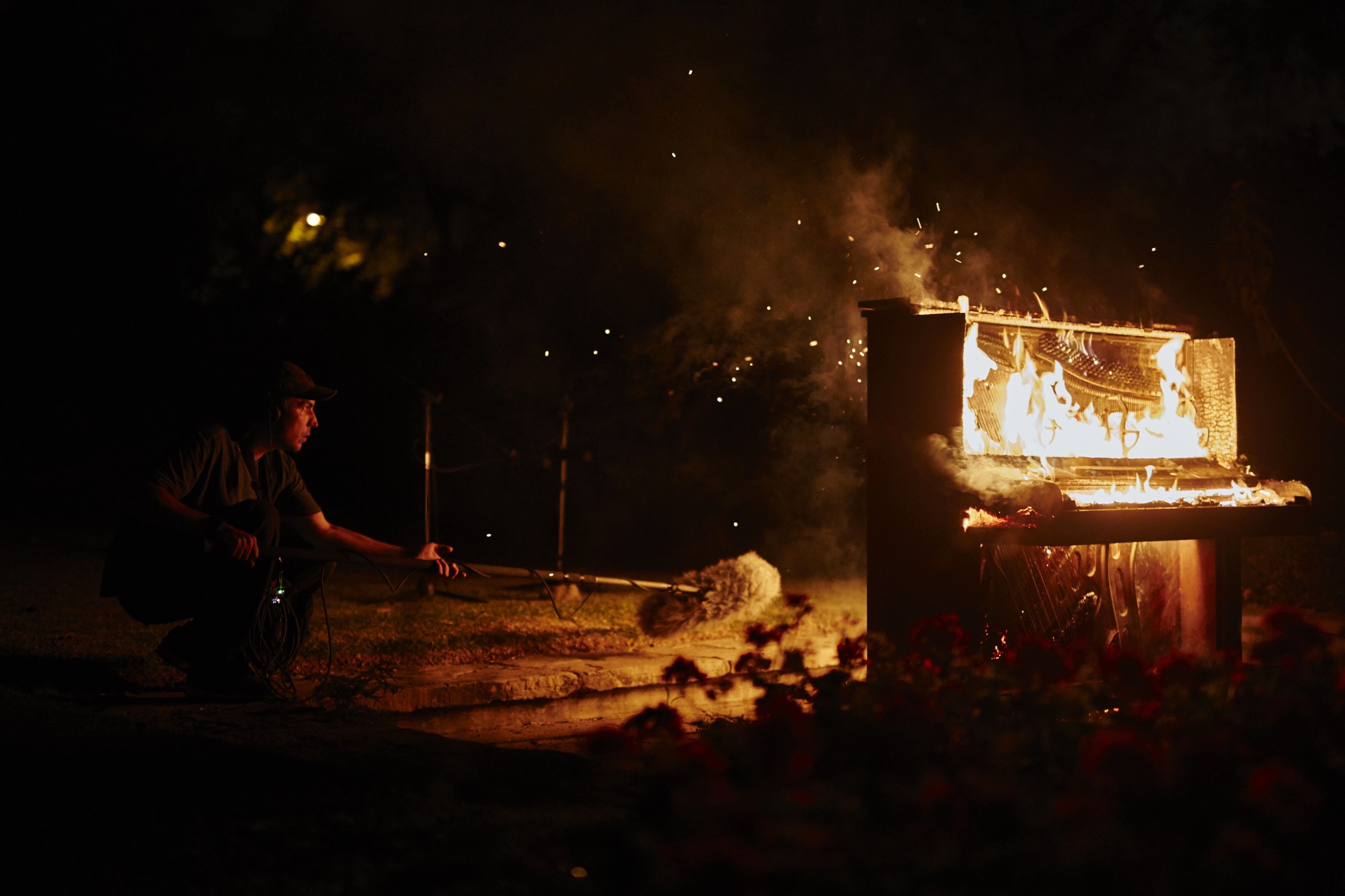 Still de Lima grita: un sonidista graba con un micrófono un piano en llamas de noche
