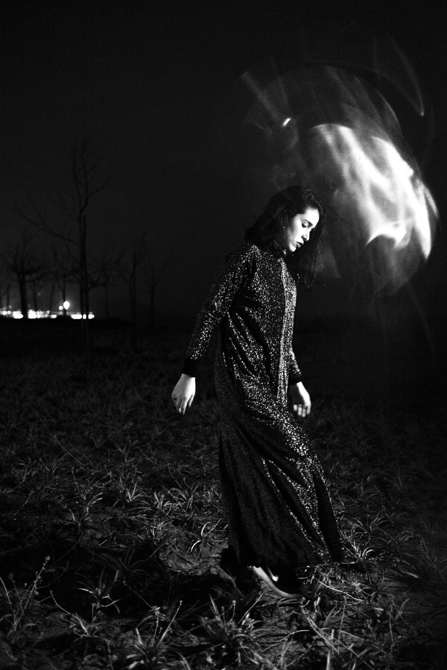 Ximena Valdivia de noche en un descampado, con un vestido de lentejuelas y una estela de luz